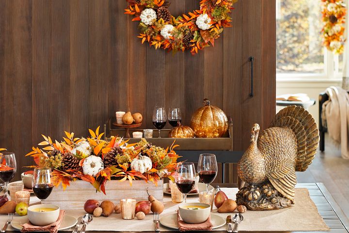 感恩节餐桌上有火鸡雕像、南瓜、树叶和梨