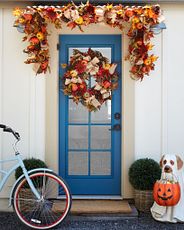 Blue front door with glass panels decorated with artificial fall wreath and garland