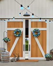 Front porch decorated with pink flower wreaths, garlands, and hanging baskets