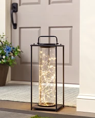 Black lantern with solar fairy lights on a verandah step