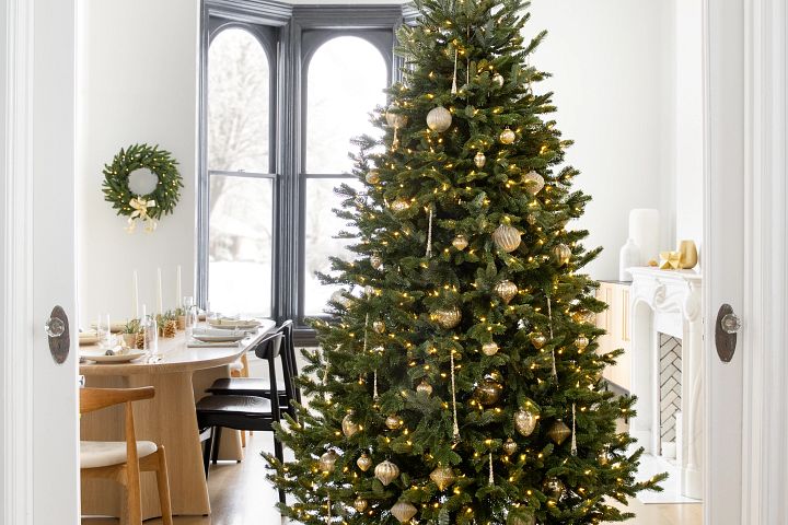 Artificial Christmas tree in dining room decorated with metallic gold ornaments