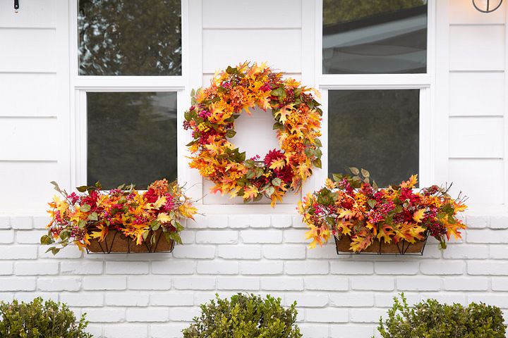 Exterior windows decorated with a fall wreath and window boxes