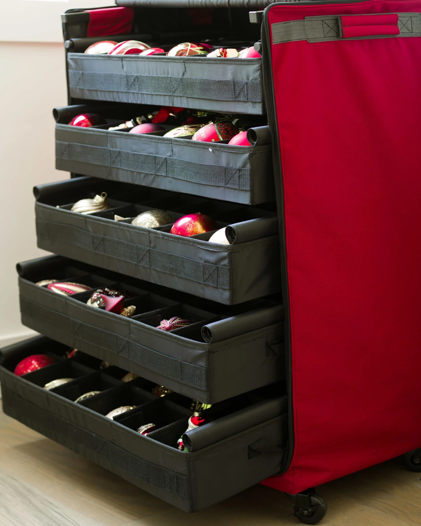 A red and black storage cart filled with various colorful Christmas ornaments ready for holiday decorating