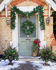 Décor de porte de Noël avec des couronnes, des guirlandes et un traîneau en bois