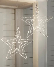 Pair of lighted star decorations hanging on a white porch
