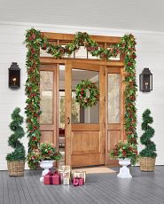 Light brown front door decorated with artificial Christmas greenery and topiaries