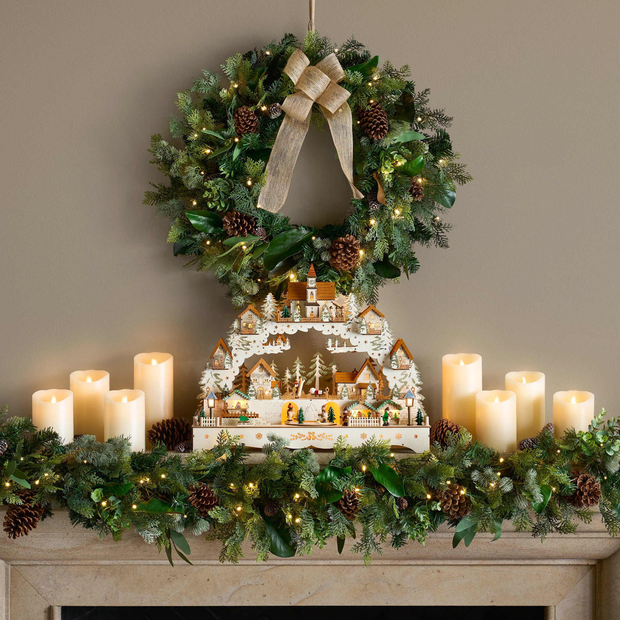 Christmas mantel decorating idea with rustic wreath and garland with flameless candles and Christmas village décor