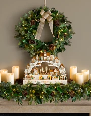 Christmas mantel decorating idea with rustic wreath and garland with flameless candles and Christmas village décor