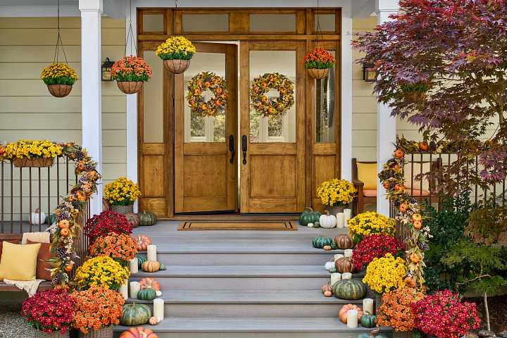 Porch decorated with autumn wreaths, garlands, urn fillers, and hanging baskets