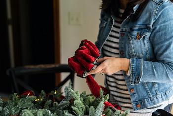 A woman creating a rosette bow to decorate a Christmas wreath