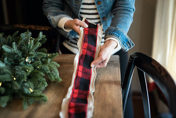 A woman layering two kinds of Christmas tree ribbons