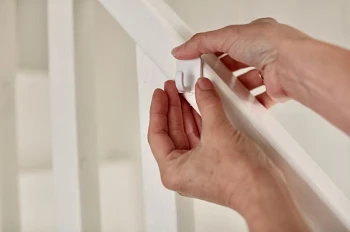 Woman’s hands sticking an adhesive hook on staircase handrails