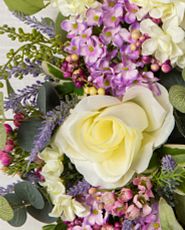 Closeup of artificial white rose and mixed flower foliage
