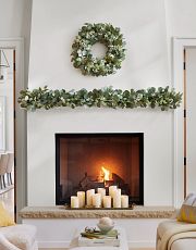 White fireplace mantel with a wreath, garland, and LED candles