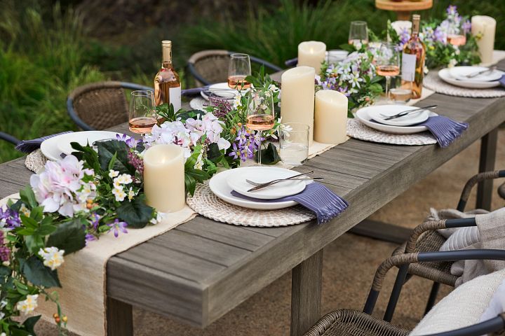 Outdoor table setting with flower garland centerpiece and candles