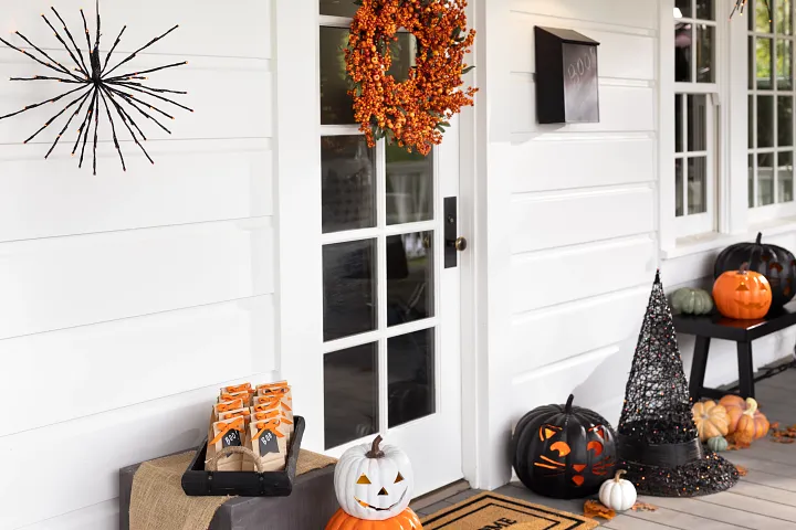 Halloween doorway decorated with wreath, pumpkins, and themed accents