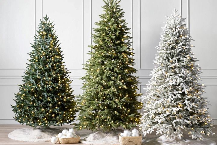 A group of three artificial Christmas trees in a white room