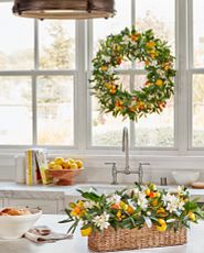 Wreath with orange and yellow blooms hanging in a sunny kitchen