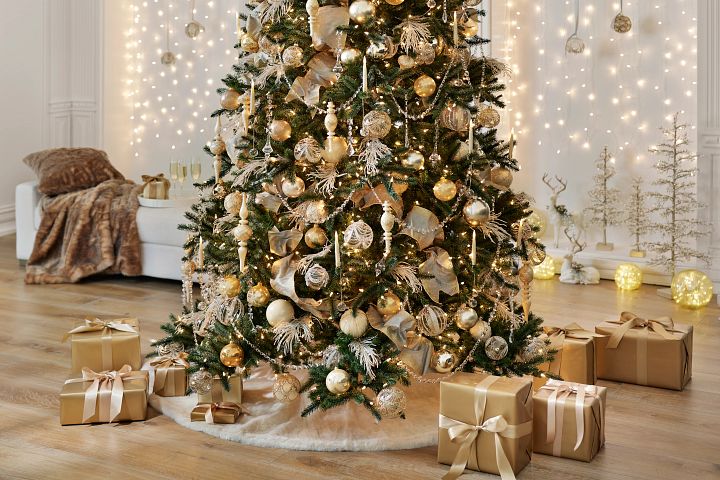 Artificial Christmas tree decorated with gold ornaments, garlands, and ribbons