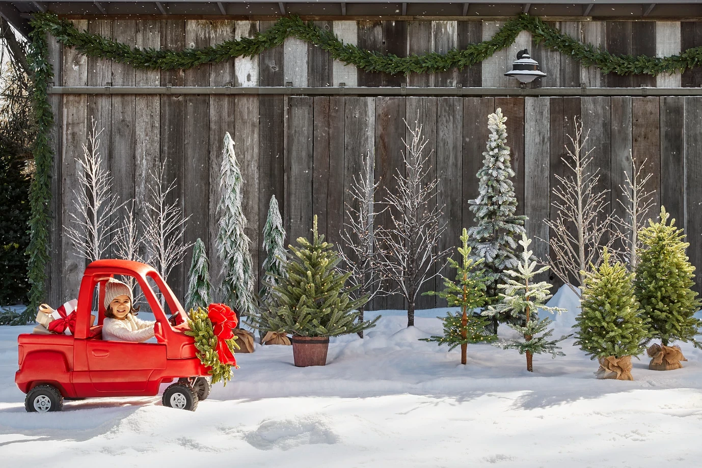 A girl driving a toy truck in a snow-covered yard