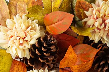 Close-up of artificial fall wreath with dahlias, pears, pinecones, and leaves