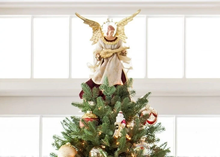 White and gold angel tree topper on top of a Christmas tree