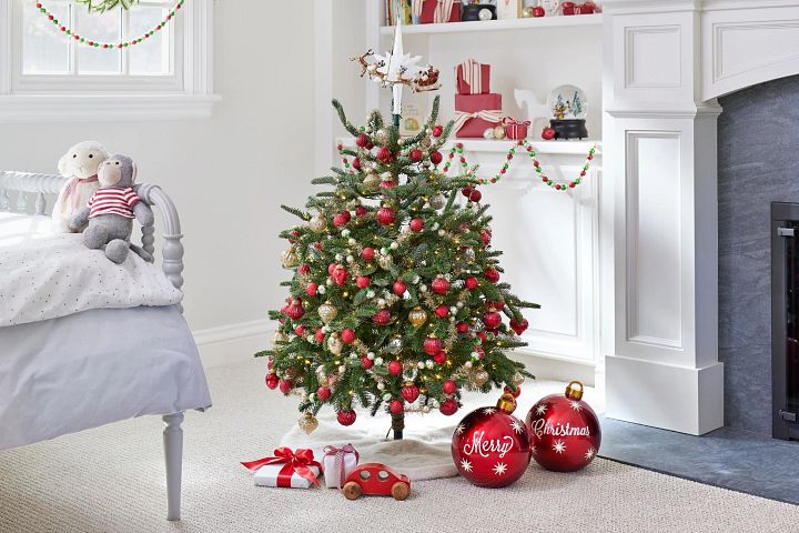 Mini artificial Christmas tree in child’s bedroom decorated with red and gold mini ornaments