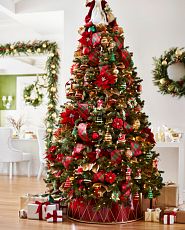Artificial Christmas tree decorated with red and green ornaments, plaid ribbons, and metallic red tree collar