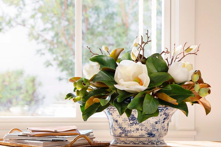 White flowers in a blue and white ceramic vase next to a window