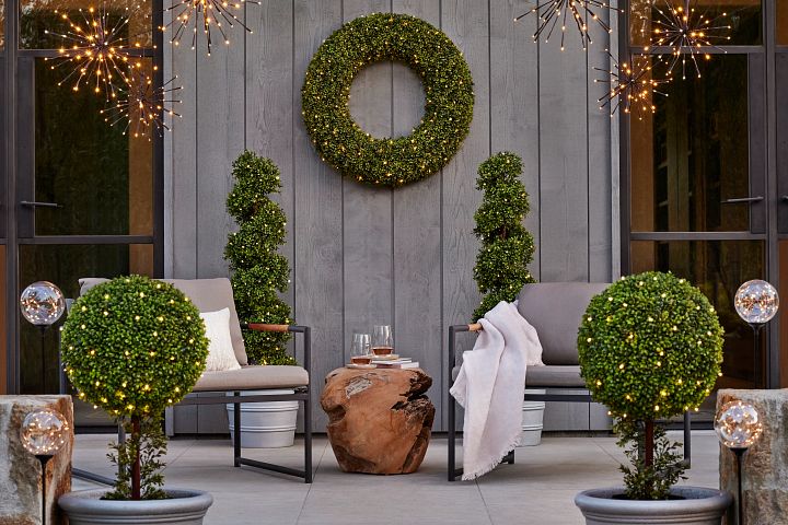 Patio seating area with artificial boxwood topiaries and  pathway lights