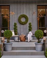 Patio adorned with an outdoor wreath and potted greenery