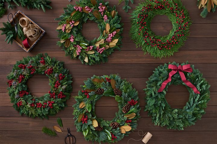 Group of fresh holiday wreaths on wood table
