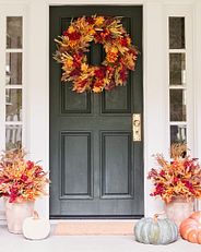 Fall-themed floral wreath and potted foliage on front door