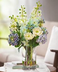 Artificial flower arrangement with violas and hydrangeas in clear vase
