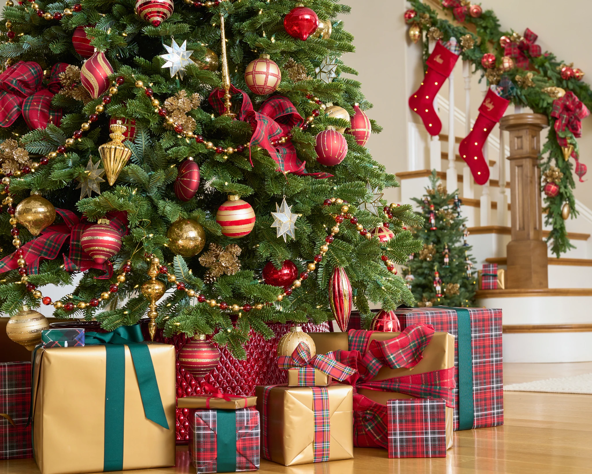 Wrapped presents underneath a Christmas tree decorated with red and gold ornaments