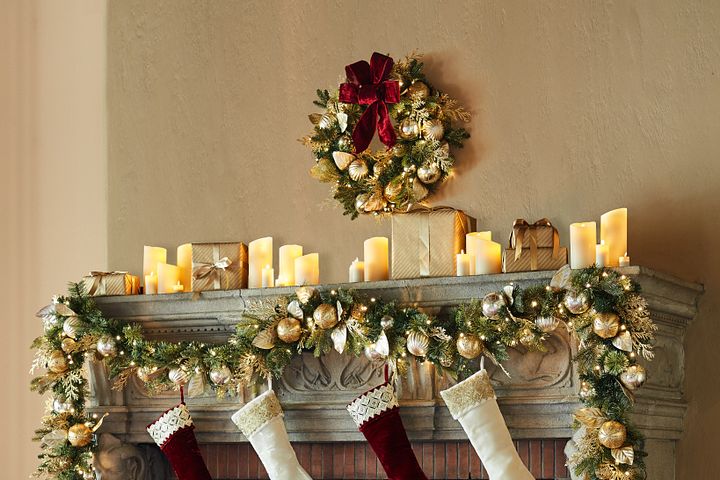 Holiday mantel showing elegant Christmas fireplace decorations like gilded greenery, flameless candles, and faux fur stockings