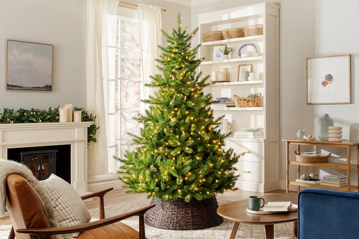 Artificial Christmas tree with lights in a living room decorated in a neutral palette