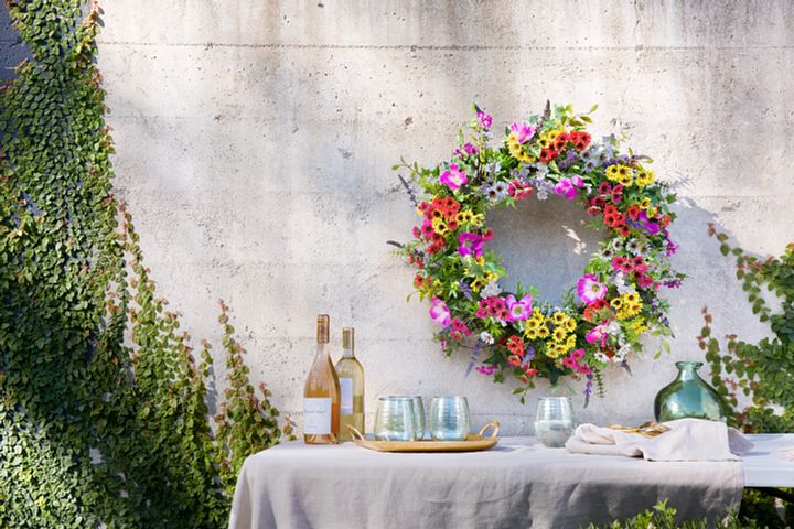 Colorful flower wreath behind a table with wine and glasses