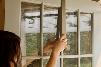 Woman hanging a metal wreath hanger over a door