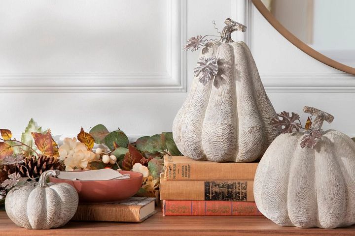 A trio of faux pumpkins set on a table with books