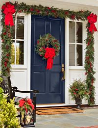 The façade of a house decorated with Christmas wreaths, garlands, and potted foliage