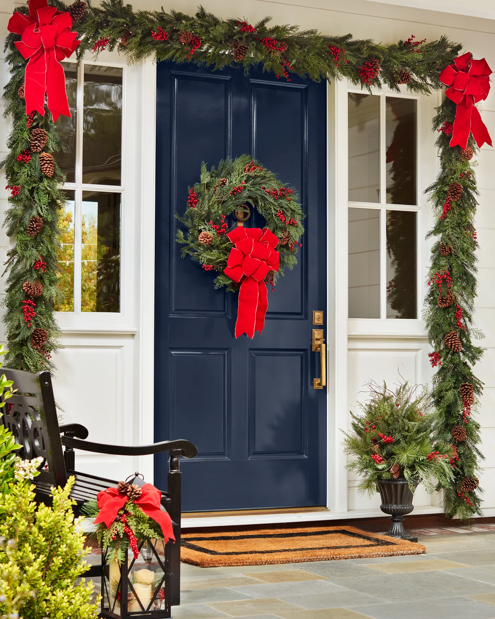 The façade of a house decorated with Christmas wreaths, garlands, and potted foliage