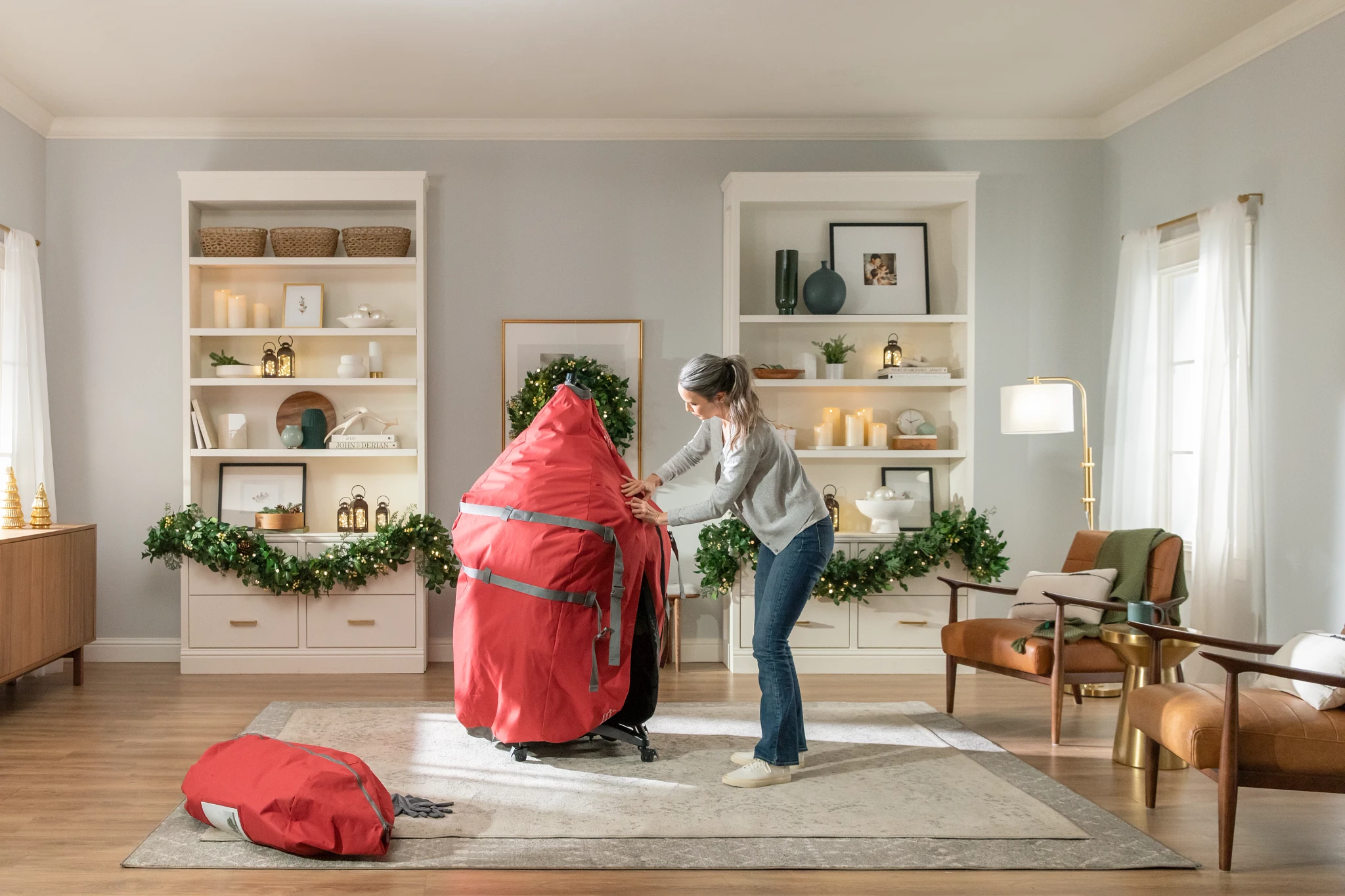 A woman storing a Christmas tree in a large red storage bag