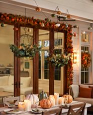 Outdoor dining area decorated with artificial fall foliage, candles, and pumpkins