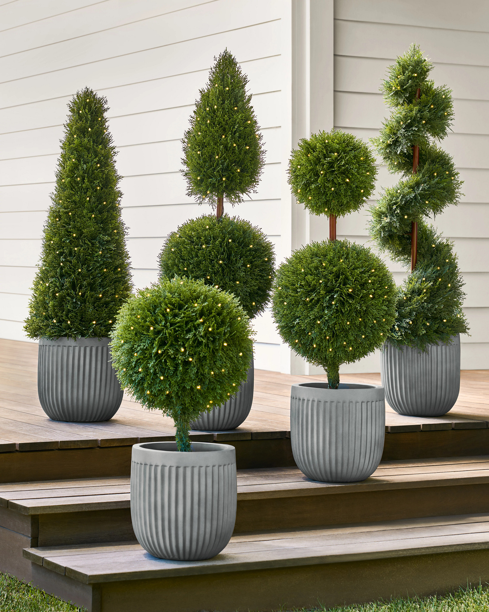 Assorted artificial cypress topiaries in gray pots