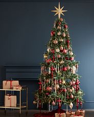 Schmaler Baum geschmückt mit Weihnachtskugeln und Girlanden