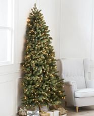Pre-lit artificial Christmas tree with a flat back set against a white wall
