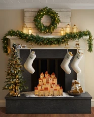 Christmas mantel decorating idea with lit wreath, garland, tabletop tree, advent calendar, and stockings