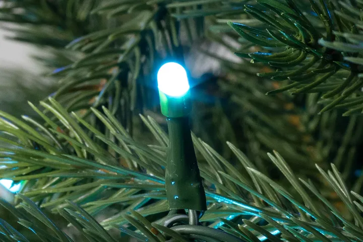 Closeup of lit blue light bulb against artificial tree needles