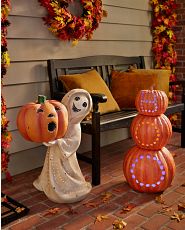 Stacked pumpkins with Boo carvings next to a ghost figurine